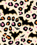 A repeating Halloween-themed pattern featuring black bats, leopard spots in black, orange, and pink, and small pink sparkles on a cream background with gold glitter-style outlines.