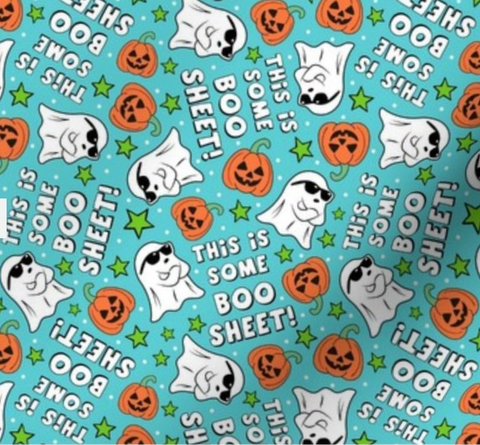A close-up of a Halloween-themed fabric pattern featuring white cartoon ghosts, orange jack-o'-lanterns, green stars, and white text reading 'THIS IS SOME BOO SHEET!' on a bright aqua background.